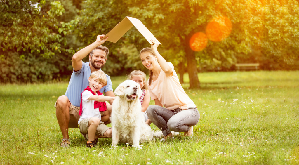 A family with a dog holding a cardboard as a roof outdoors