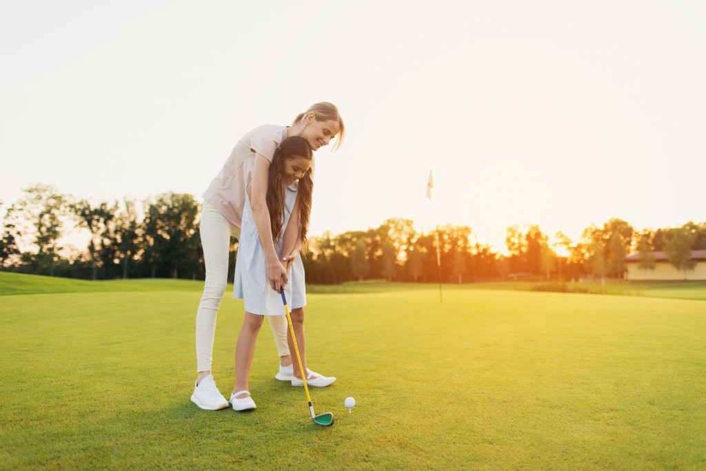 mother teaching daughter to play golf