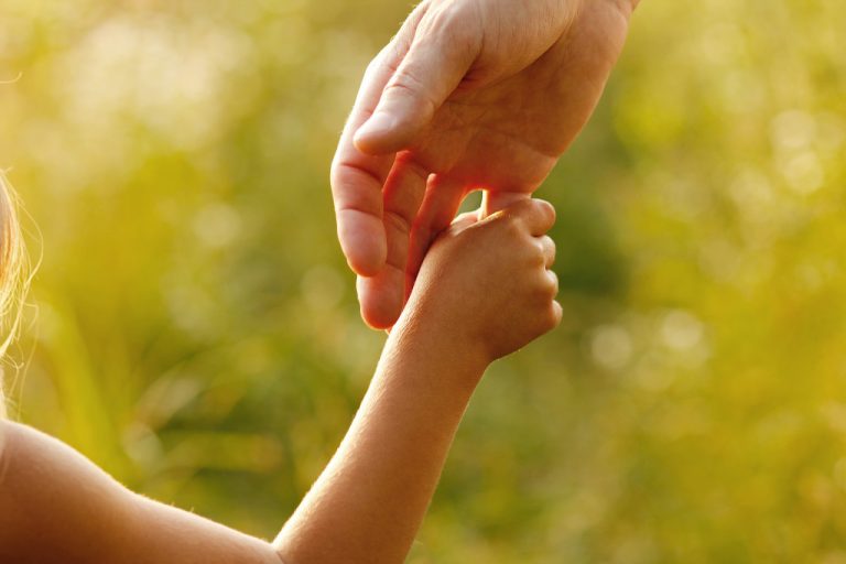 kid holding the hand of his or her parent