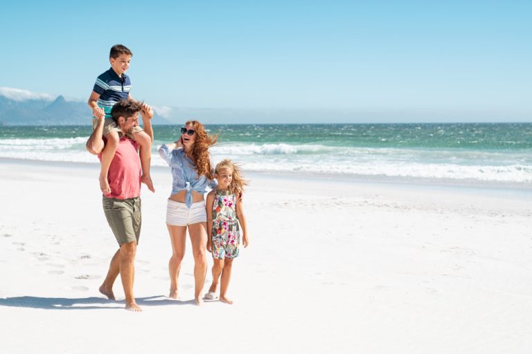 A young family walking on the beach on a sunny day