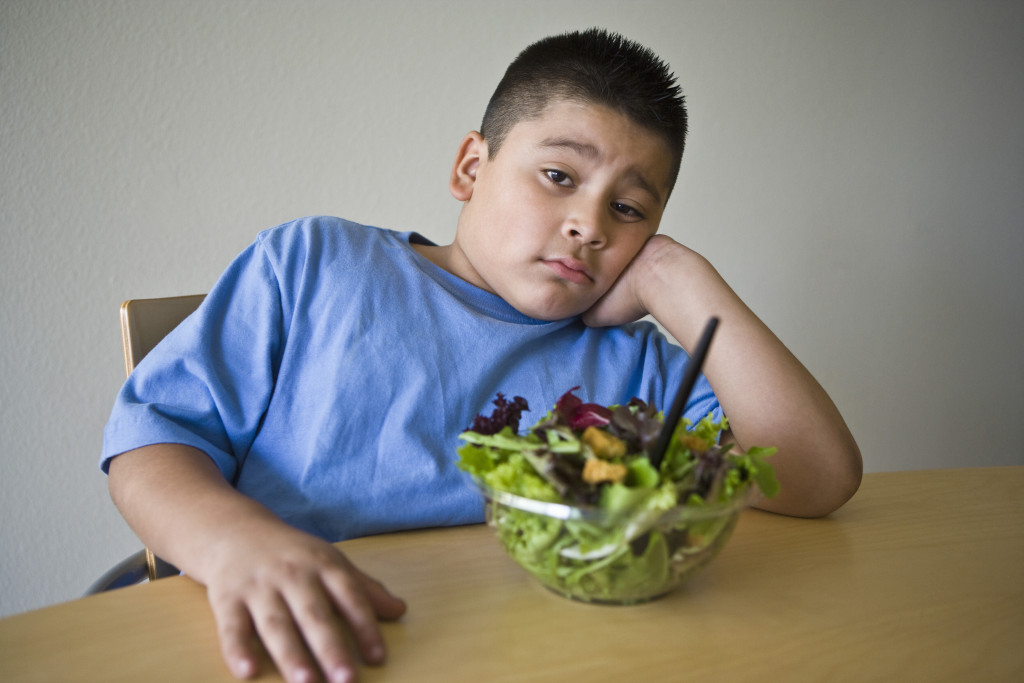 a boy eating vegetable salad